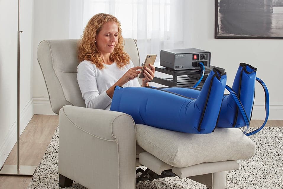 Patient at home using pneumatic compression sleeves connected to a sequential circulator pump
